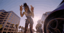 a woman is standing in front of a car and giving the peace sign