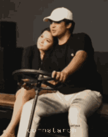 a man in a white hat sits next to a woman on a couch