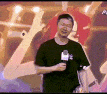 a man in a black shirt is holding a microphone in front of a painting .