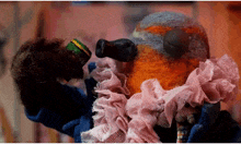 a stuffed animal is wearing a blue jacket and a pink lace ruffle