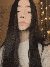 a girl with long black hair is wearing a white t-shirt and looking at the camera .
