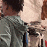 a person in a green hoodie is standing in a closet