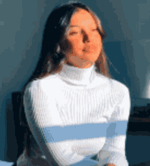 a woman wearing a white sweater with blue stripes on the sleeves