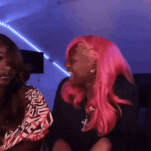 a woman with pink hair is laughing with another woman in a purple room