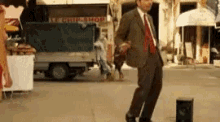 a man in a suit and tie is dancing on the street