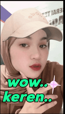 a woman wearing a hat and a hijab says wow keren in green letters