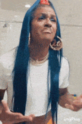 a woman with blue hair is wearing a white shirt and gold hoop earrings