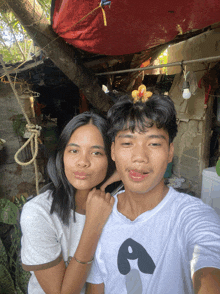 a man and a woman are posing for a picture with the man wearing a shirt with the letter a on it