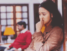 a woman covering her nose with her hand while a man sits behind her