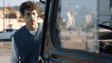 a man in a blue vest is looking out of a car window