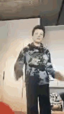 a young man is dancing in a kitchen in a blurry photo .