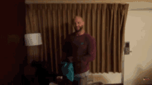 a man with a beard is standing in front of a curtain in a room