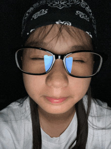 a girl wearing glasses has her eyes closed and a bandana around her head