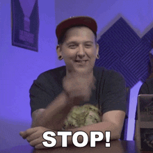 a man sitting at a table with his fist in the air and the word stop below him