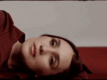 a woman in a red shirt is laying down