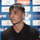 a man in a black shirt stands in front of a banner that says estrella
