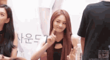 a woman with long red hair is giving a peace sign while standing next to a man in a black shirt