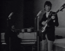 a man is playing a guitar and a woman is playing a piano on stage .
