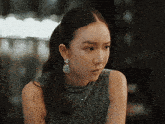 a woman wearing a ponytail and earrings is looking at the camera