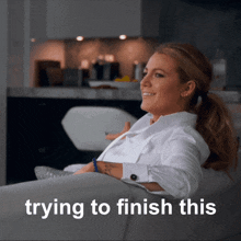 a woman sits on a couch with the words " trying to finish this " behind her