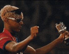 a man wearing sunglasses is holding a trophy that says ambitious on it