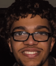 a young man with glasses and a beard smiles for the camera