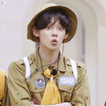 a young man in a scout uniform is wearing a hat and making a funny face .