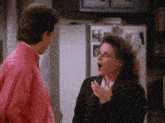 a man in a pink shirt stands next to a woman in a black sweater