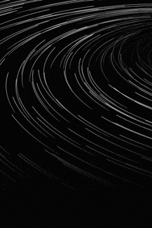 a black and white photo of a circular pattern of stars in the night sky .