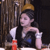 a woman is sitting at a table with a can of coca cola and a glass of soda .