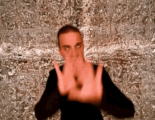 a man making a stop sign with his hands in front of a silver background