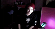 a man wearing headphones and a red beanie is dancing in front of a microphone