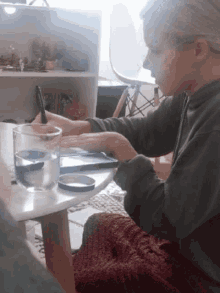 a person sits at a table with a glass of water and a pen