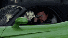 a man is sitting in a green sports car with sunglasses on
