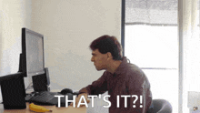 a man sits at a desk with a computer and the words that 's it behind him