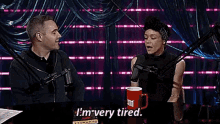 a man and a woman are sitting at a table in front of microphones and talking .