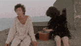 a man in a white shirt sits next to a woman in a black feathered outfit
