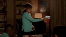 a woman in a blue sweater is standing in a living room holding a bottle of soda .
