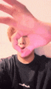 a person making a heart shape with their hands while wearing a black shirt that says " about " on it