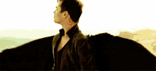 a man in a black jacket is standing with his arms outstretched