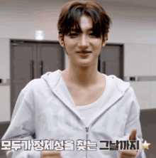 a young man wearing a white hoodie is giving a thumbs up sign in korean