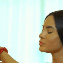 a woman wearing a red bracelet on her wrist is being sprayed with perfume