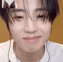 a close up of a young man wearing headphones and a white shirt smiling .
