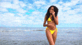a woman in a yellow bikini is standing in the ocean