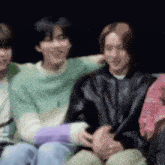 a group of young people are sitting next to each other on a couch and laughing .