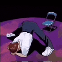 a man is laying on his back on a purple surface next to a chair .