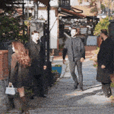 a group of people are standing on a sidewalk in front of a restaurant .