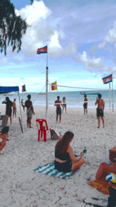 a group of people are playing volleyball on a beach with a flag that says ' cambodia ' on it