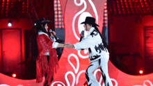 a man in a cowboy hat and a woman in a red poncho are singing into microphones on a stage .