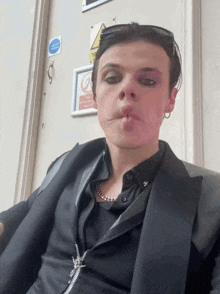 a man in a black jacket is smoking a cigarette in front of a sign that says no smoking